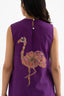 A woman in a sleeveless purple dress with a block-print flamingo on the back.